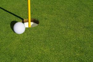 close-up do verde do campo de golfe, pino de bandeira e bola. foto