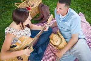 jovem adulta tocando violão com o namorado no parque. foto