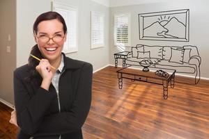 mulher com lápis no quarto vazio da casa nova com sofá e mesa de desenho na parede foto