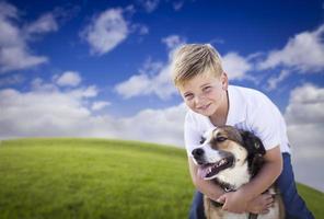 menino bonito brincando com seu cachorro na grama foto