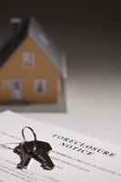 aviso de execução duma hipoteca, chaves de casa e casa modelo em fundo graduado foto