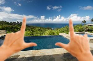 mãos emoldurando piscina e pátio com vista para o mar foto