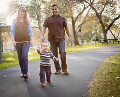 feliz família étnica de raça mista caminhando no parque foto