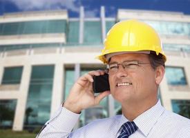 empreiteiro de capacete fala ao telefone em frente ao prédio foto