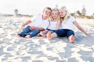 adoráveis irmãs e irmão se divertindo na praia foto
