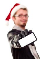 homem com chapéu de papai noel segurando celular em branco foto