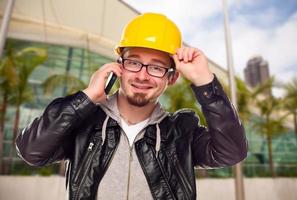 jovem trabalhador da construção civil no celular em frente ao prédio foto