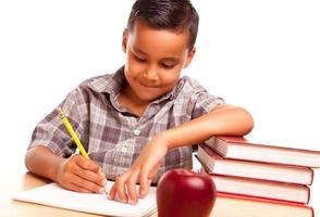 adorável menino hispânico com livros, maçã, lápis e papel foto