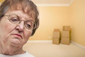 mulher mais velha triste no quarto vazio com caixas foto