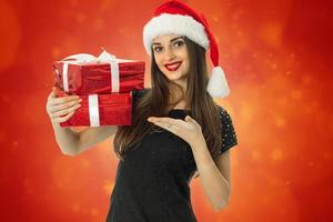 menina alegre com chapéu de Papai Noel com presente vermelho foto