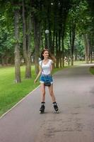 linda garota feliz em shorts patins no parque foto