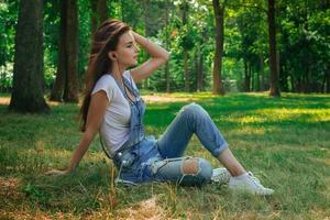 jovem adorável senta-se em uma grama e ouvindo música foto