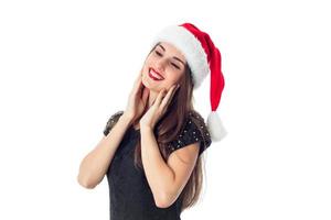 menina morena com chapéu de Papai Noel com os olhos fechados foto