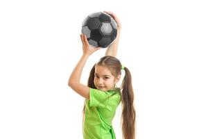 retrato de uma menina que é levantada acima da cabeça bola de futebol foto