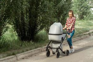 jovem mãe caminha com carrinho no parque foto