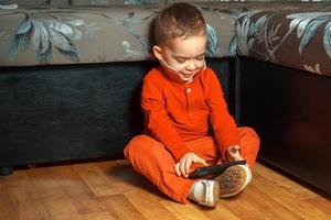 menino de terno vermelho jogando jogos para celular foto