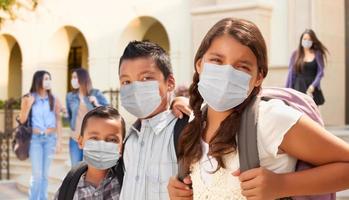 jovens estudantes no campus da escola usando máscaras faciais médicas foto