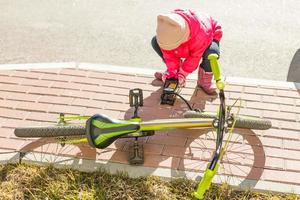 uma garotinha enche um pneu de bicicleta foto