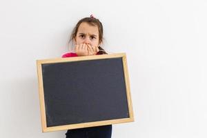 menina bonitinha segurando um quadro-negro, isolado no branco foto