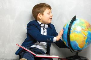 garoto curioso feliz menino gênio em fundo cinza foto