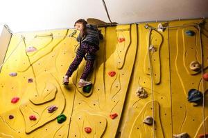 menina escalando parede de pedra foto