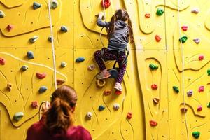 menina escalando uma parede de pedra interior foto