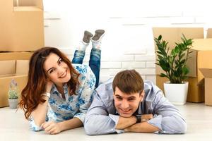 casal sorridente, apoiando-se em caixas na nova casa foto