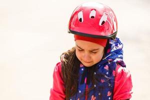 linda menina morena usando capacete de bicicleta e colete reflexivo com expressão triste chorando. conceito de depressão. foto