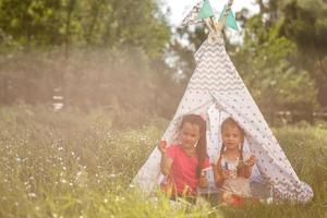 duas garotinhas rindo felizes na barraca de acampamento no campo-leão foto