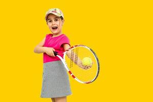 foto de estúdio de corpo inteiro de menina de sete anos segurando raquete de tênis e bola de tênis isolada laranja