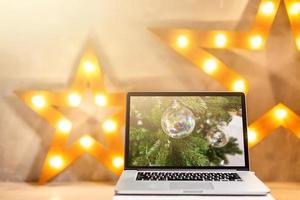 imagem de laptop aberto com tela branca na mesa de madeira na frente do fundo da árvore de natal. para maquete foto