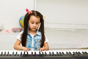 menina bonitinha toca piano, sintetizador. Treinamento. Educação. escola. formação estética. sala de aula elementar.