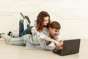 casal fazendo compras on-line no computador portátil - dois jovens amigos assistindo a um vídeo em um notebook na sala de estar foto