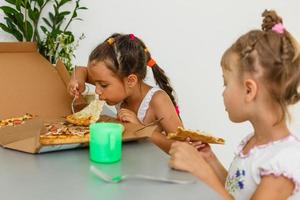 dois amigos segurando pizza - se divertindo jantando - conceito rebelde - foco na fatia esquerda foto