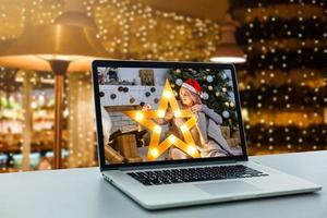 menina no computador e chapéu de natal foto