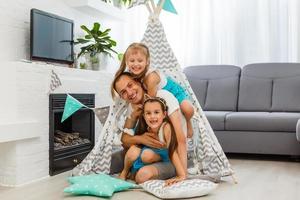 pai e filha deitados no chão dentro de tenda e olhando para a câmera em casa foto