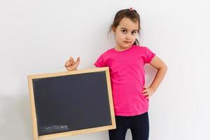 menina bonitinha segurando um quadro-negro, isolado no branco foto