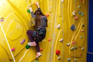 menina escalando parede de pedra foto