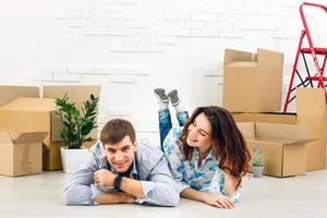 casal sorridente, apoiando-se em caixas na nova casa foto