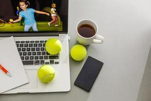 jogador de tênis esportivo com raquete em traje azul. mulher atleta. laptop na mesa com design para publicidade de casas de apostas foto