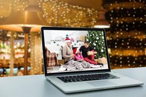 família sorridente no chão em frente ao laptop de exibição de árvore de natal na mesa. notebooks foto