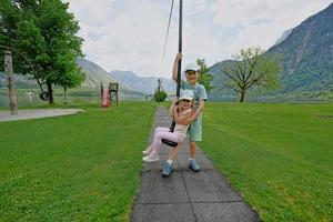 irmão com irmã balançando no playground em hallstatt, áustria. foto