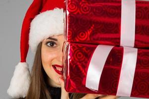 mulher de suéter quente e chapéu de Papai Noel com presente vermelho foto