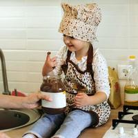 menina bonitinha come creme de chocolate na cozinha branca em casa foto