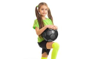 menina bonitinha na camisa verde com bola de futebol nas mãos foto