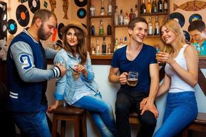 dois casais apaixonados se divertindo em um bar e bebem bebidas alcoólicas foto