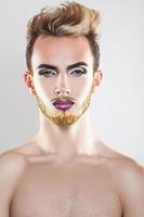 retrato vertical da gracinha jovem modelo gay com maquiagem e barba multicolorida