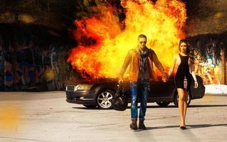 imagem horizontal do blockbuster como um homem e uma mulher saindo do carro em chamas foto