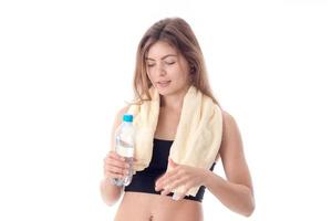 jovem atlética com a toalha nos ombros segurando a garrafa de água na mão isolado fundo branco foto