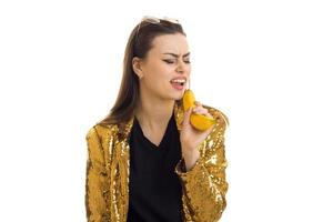garota engraçada na jaqueta dourada canta na banana foto